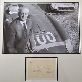 Lot 113 - A signed by Enzo Ferrari official Ferrari postcard presented with a photograph of Enzo taken at the factory in Maranello